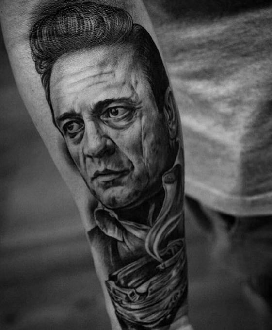 Black and gray tattoo of Johnny Cash's serious face on an arm