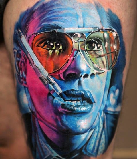 Vibrant Hunter S. Thompson tattoo featuring a hyper-realistic portrait with multicolored lighting, aviator glasses, a cigarette, and bold shading.