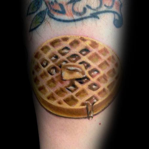 Realistic waffle tattoo with rich shading, melted butter, and dripping syrup, creating a detailed and lifelike breakfast-inspired design.
