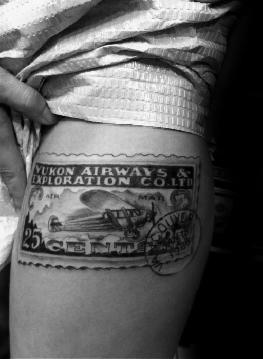 A tattoo of a vintage Yukon Airways postage stamp, elegantly capturing a biplane in flight