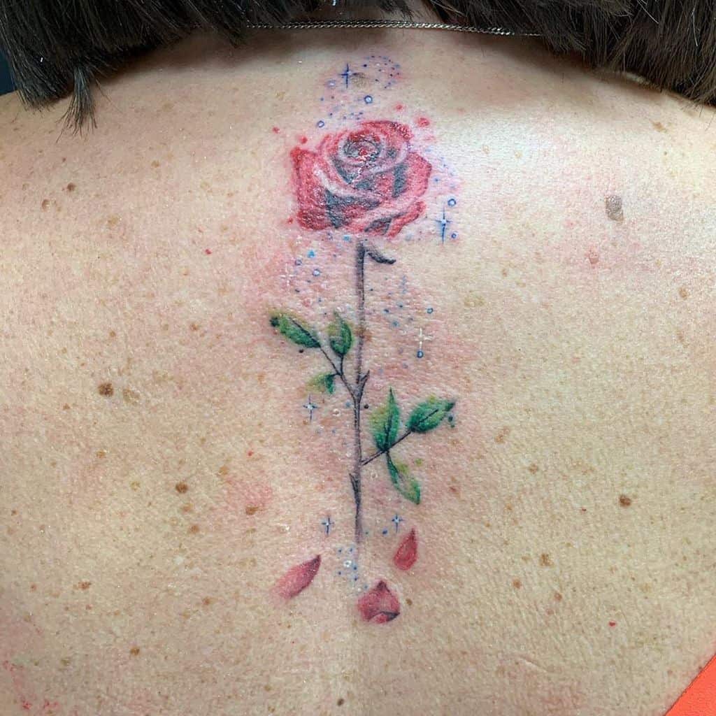 Rose tattoo with leaves and dew drops on an upper back