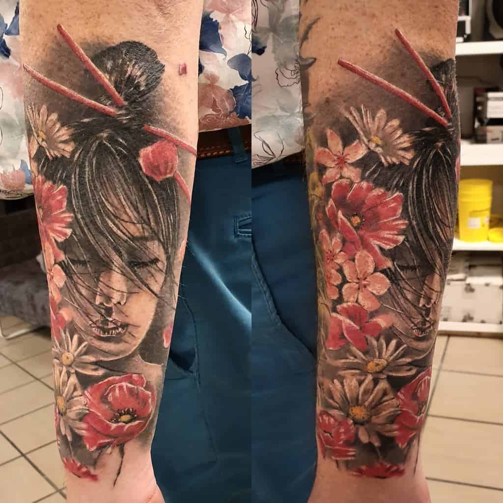 Realistic full-sleeve tattoo of a Geisha with closed eyes, intricate floral hair ornaments, and vibrant red and white flowers surrounding her face.