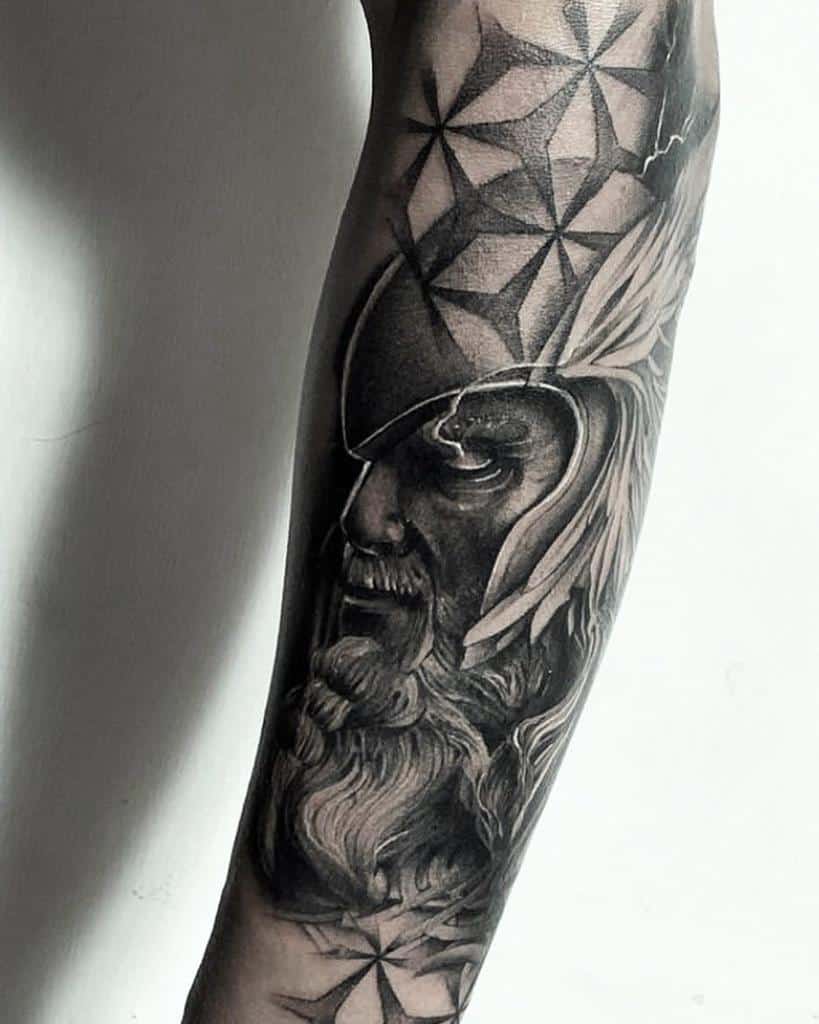 Arm tattoo depicting a bearded warrior in a helmet with geometric patterns in black and gray tones