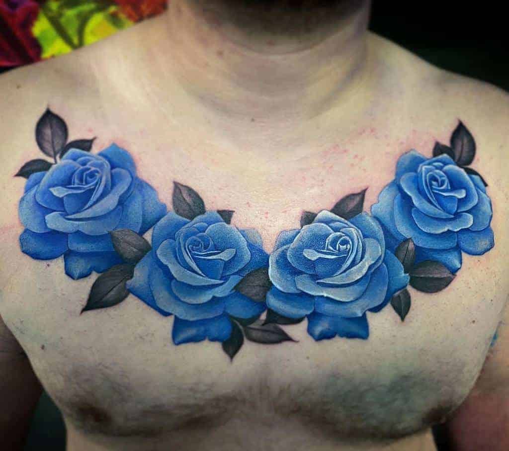 Chest tattoo of vibrant blue roses with dark leaves across the upper chest