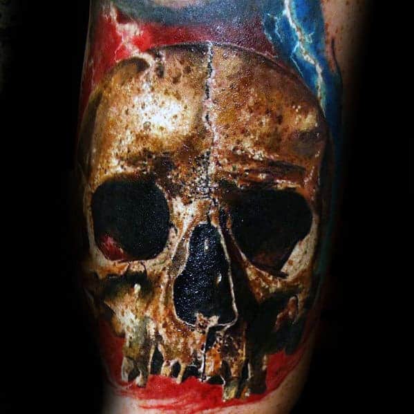 Tattoo of a realistic skull with cracks and colorful background on the skin