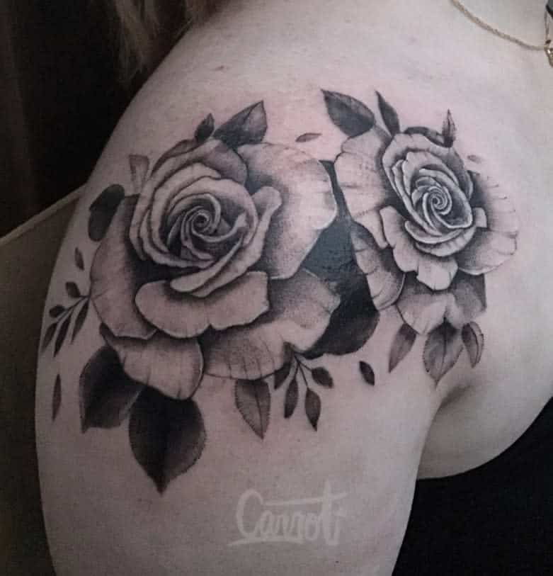 Black and gray tattoo of two roses with leaves on a shoulder