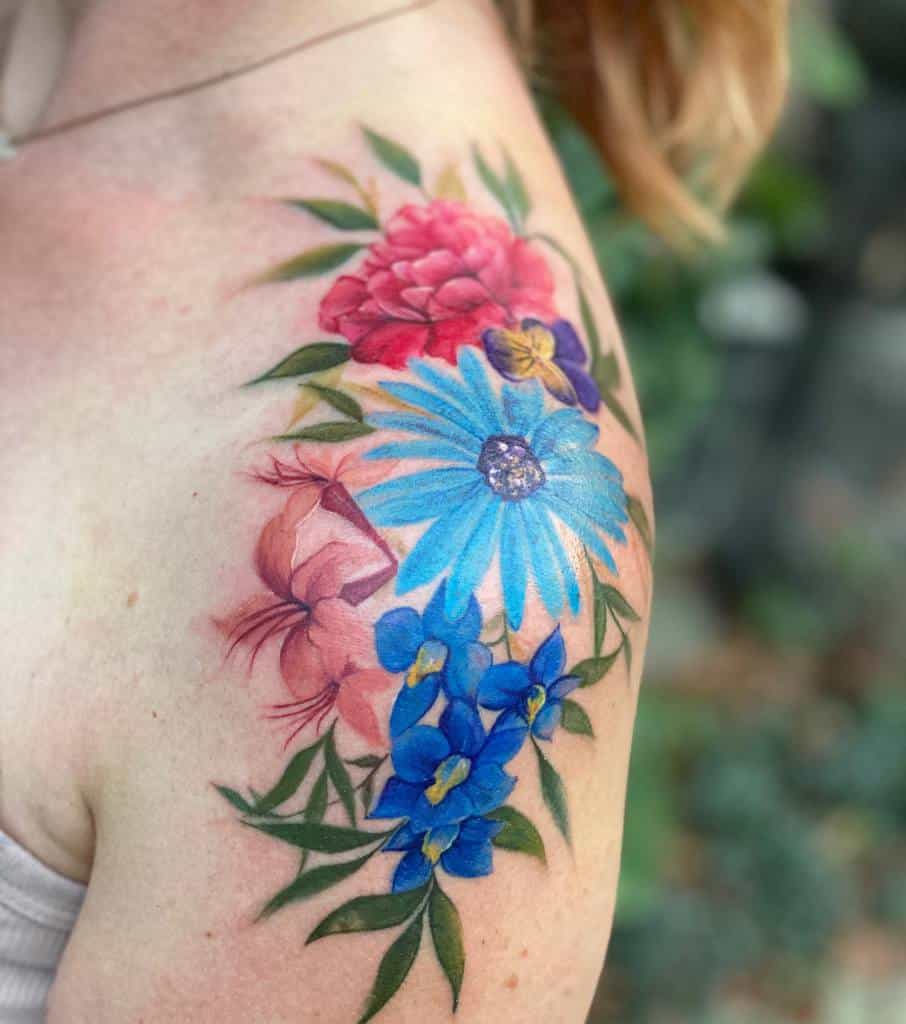 A vibrant floral tattoo graces the upper arm and shoulder, showcasing a stunning array of pink, blue, red, and purple flowers