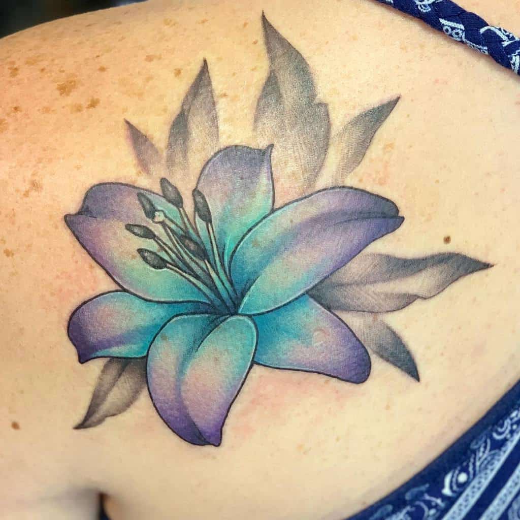 A vibrant blue and purple lily tattoo with grey leaves elegantly adorns the shoulder, creating a stunning visual masterpiece