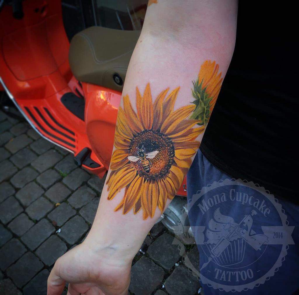 Realistic forearm tattoo of a sunflower with a bee in the center