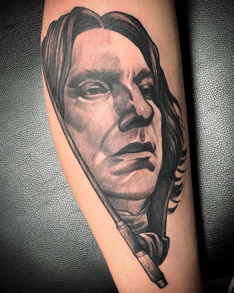 Black and grey tattoo of Severus Snape with intense shading, featuring his wand in the foreground for a bold, dramatic effect