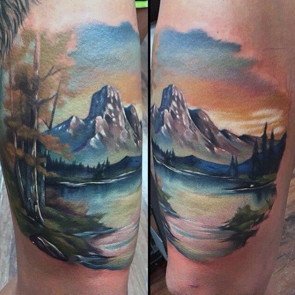 Colorful mountain lake tattoo with soft pastel skies, tree silhouettes, and water reflections, designed in a painterly, scenic style.
