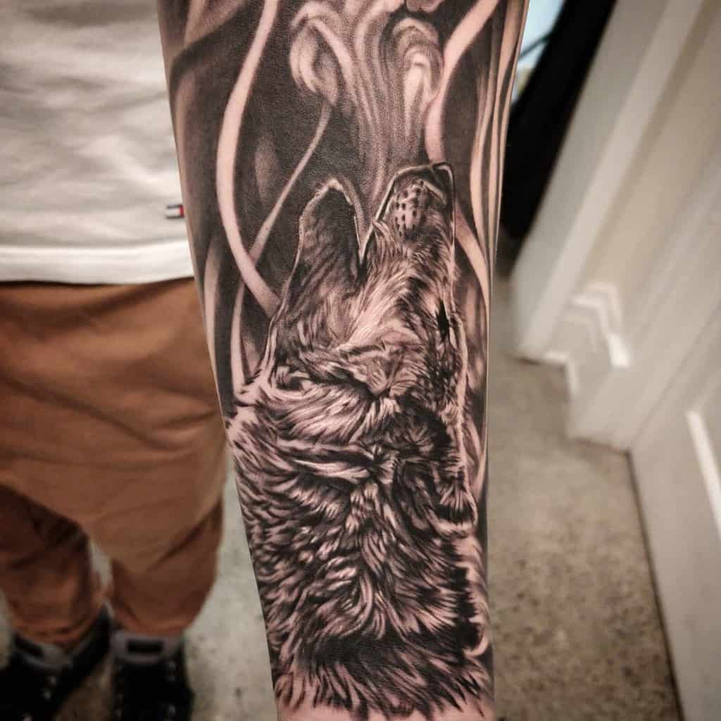 Forearm tattoo of a wolf howling, surrounded by abstract shapes