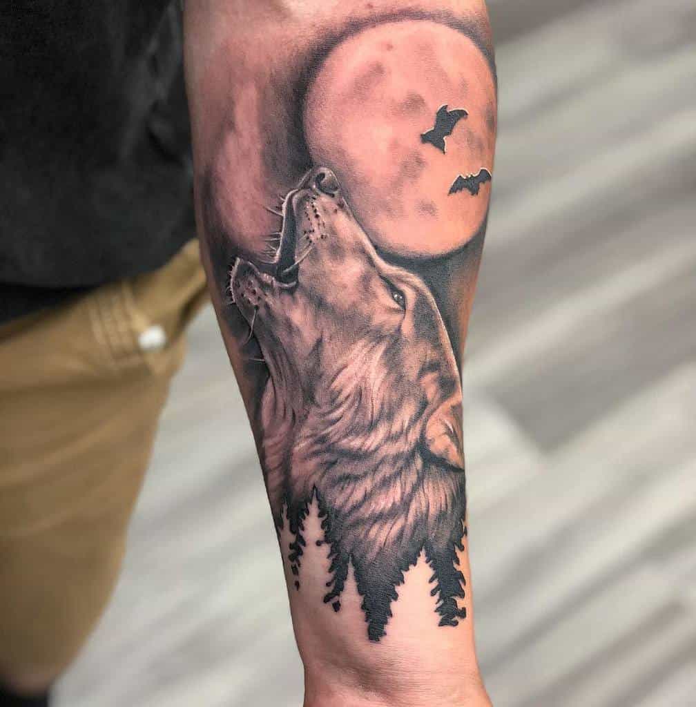 Wolf tattoo on forearm with trees, full moon, and bats in the background