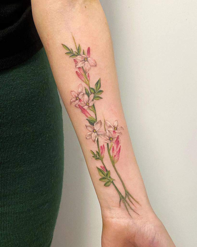 Forearm tattoo of jasmine flowers with green stems and leaves