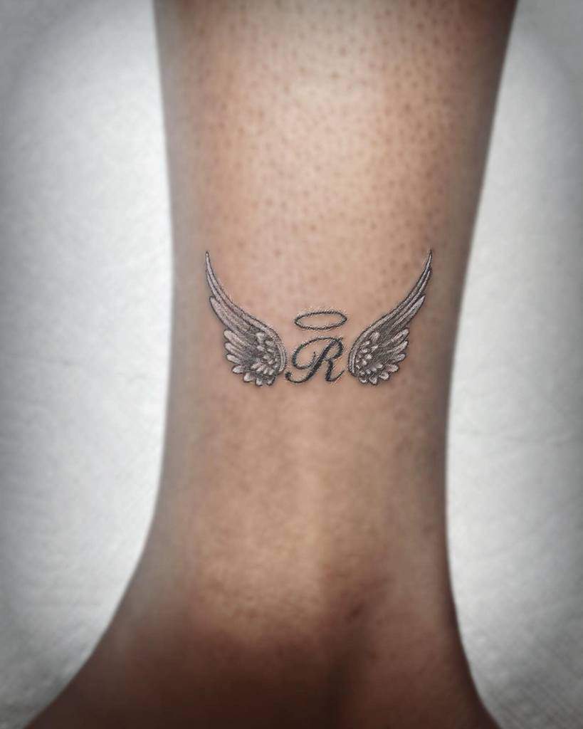 A small tattoo of the letter "R" with angel wings and a halo