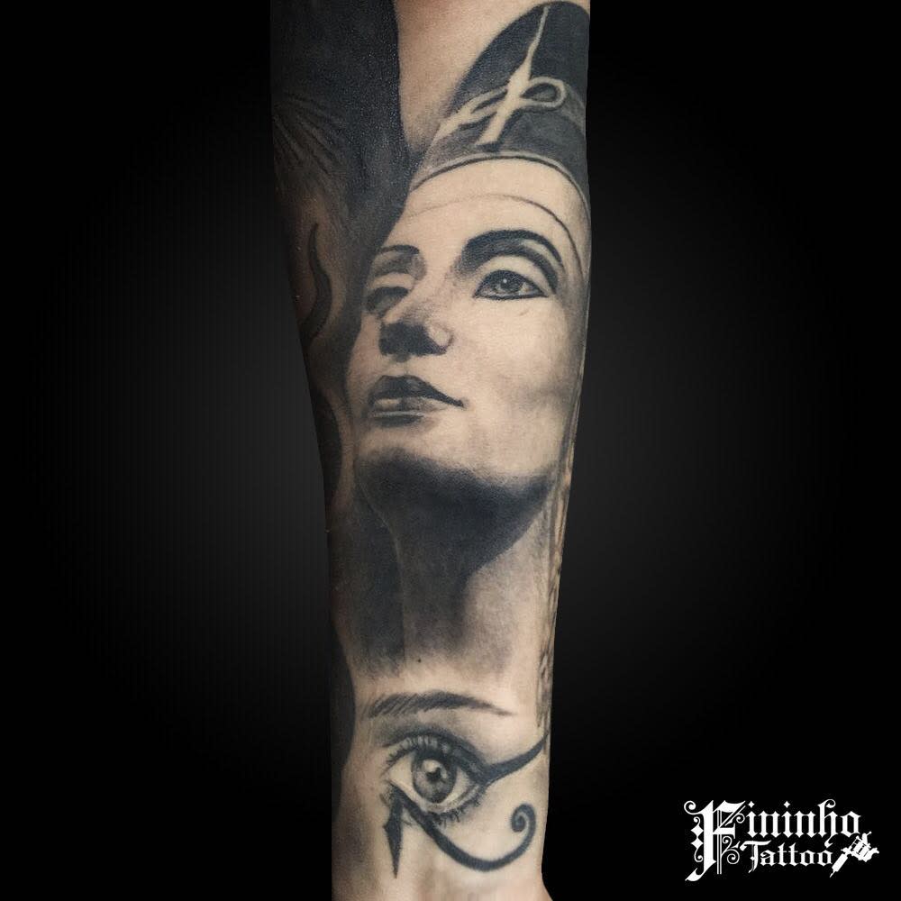Stunning tattoo captures a realistic portrayal of Queen Nefertiti, paired with the iconic Eye of Horus for a striking balance between historical beauty and symbolic depth