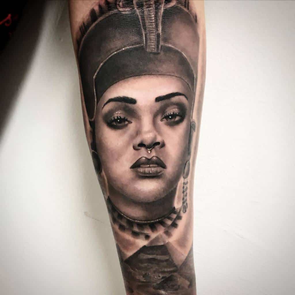 Detailed tattoo featuring Rihanna's face inspired by an ancient Egyptian queen with jewelry and a headdress