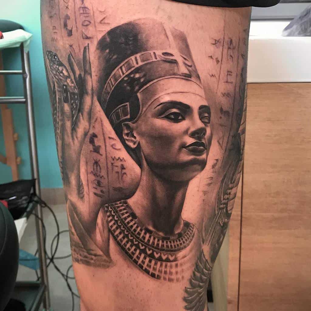 Breathtaking tattoo offers a hyper-realistic depiction of Queen Nefertiti, enriched with hieroglyphic details and a coiled serpent for a deeply immersive and historical vibe