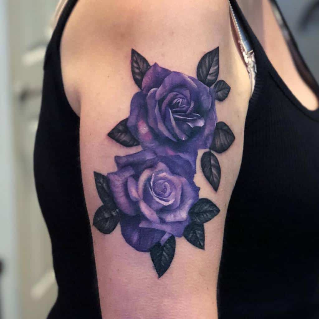 Tattoo of two purple roses with green leaves on an upper arm