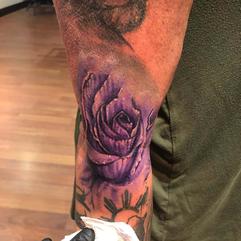 A purple rose tattoo on a man's arm
