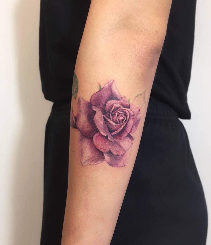 A realistic purple rose tattoo on a forearm