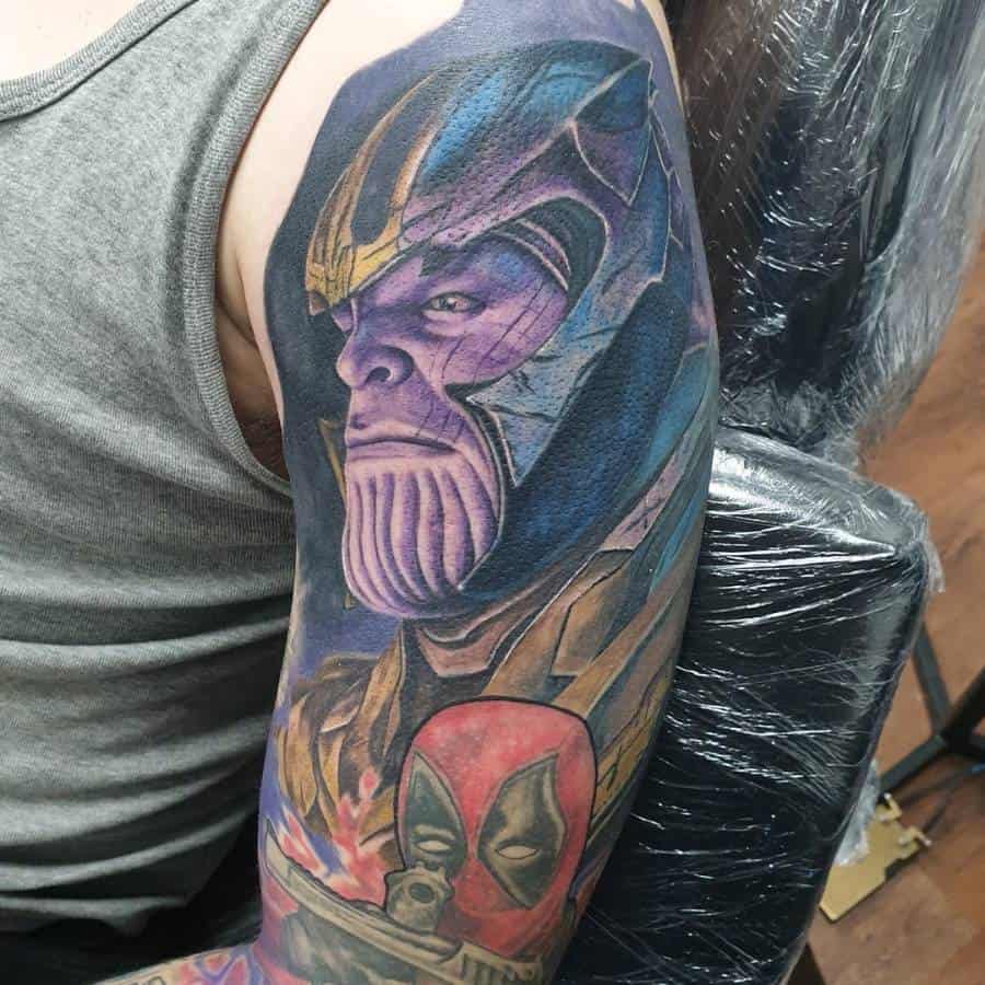 A colorful tattoo of Thanos, showcasing his intense expression in purple and blue tones, with Deadpool appearing below him in the design