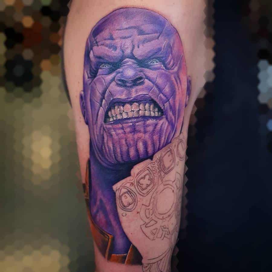 A vibrant tattoo of Thanos' face, showing his intense, grinning expression in purple tones, with the beginning of the Infinity Gauntlet