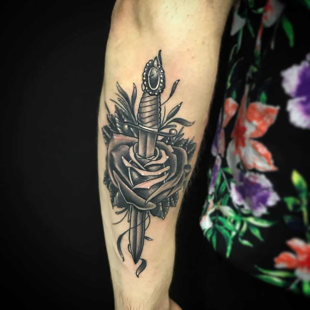 Traditional arm tattoo of a dagger through a rose