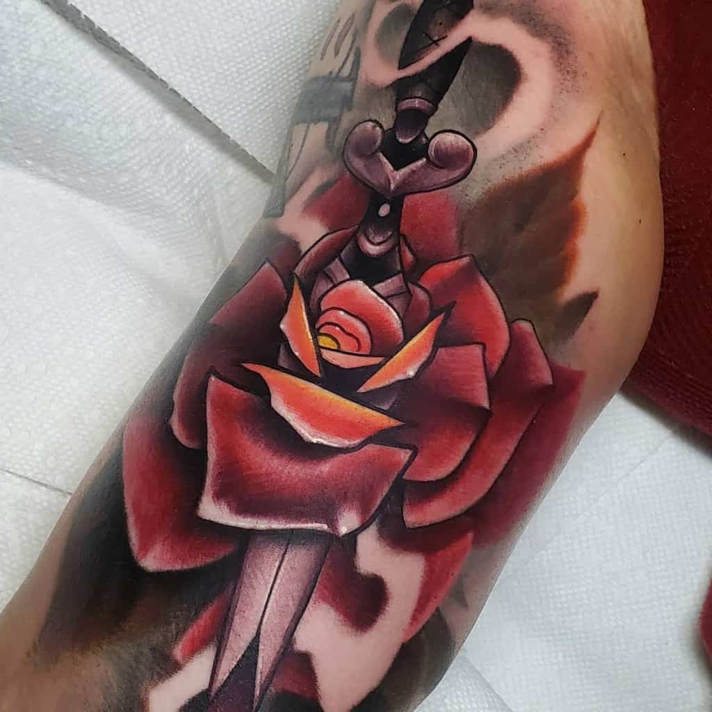 Close-up of a detailed tattoo of a dagger piercing a rose, inked on a forearm