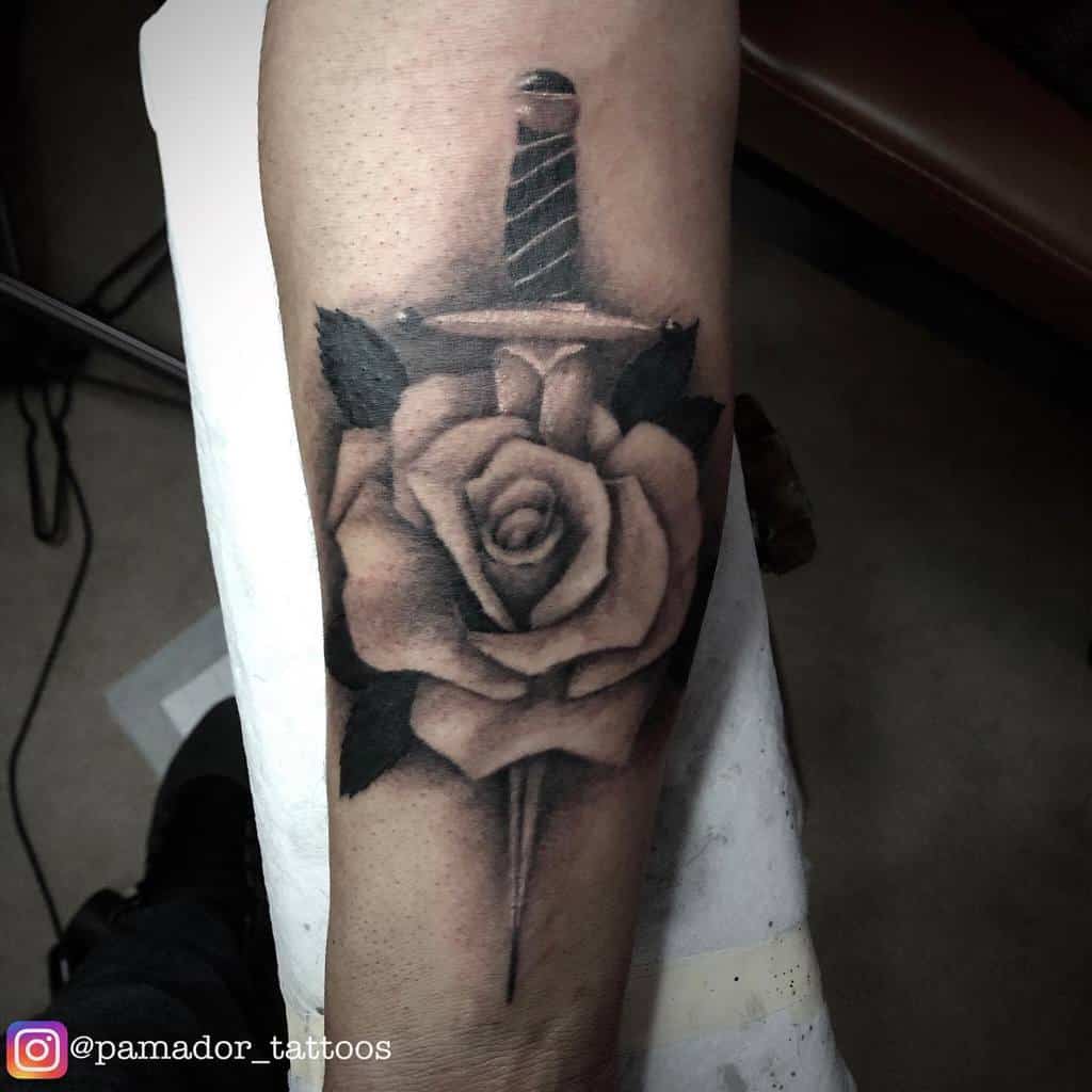 Traditional tattoo of a sword piercing a rose on an arm