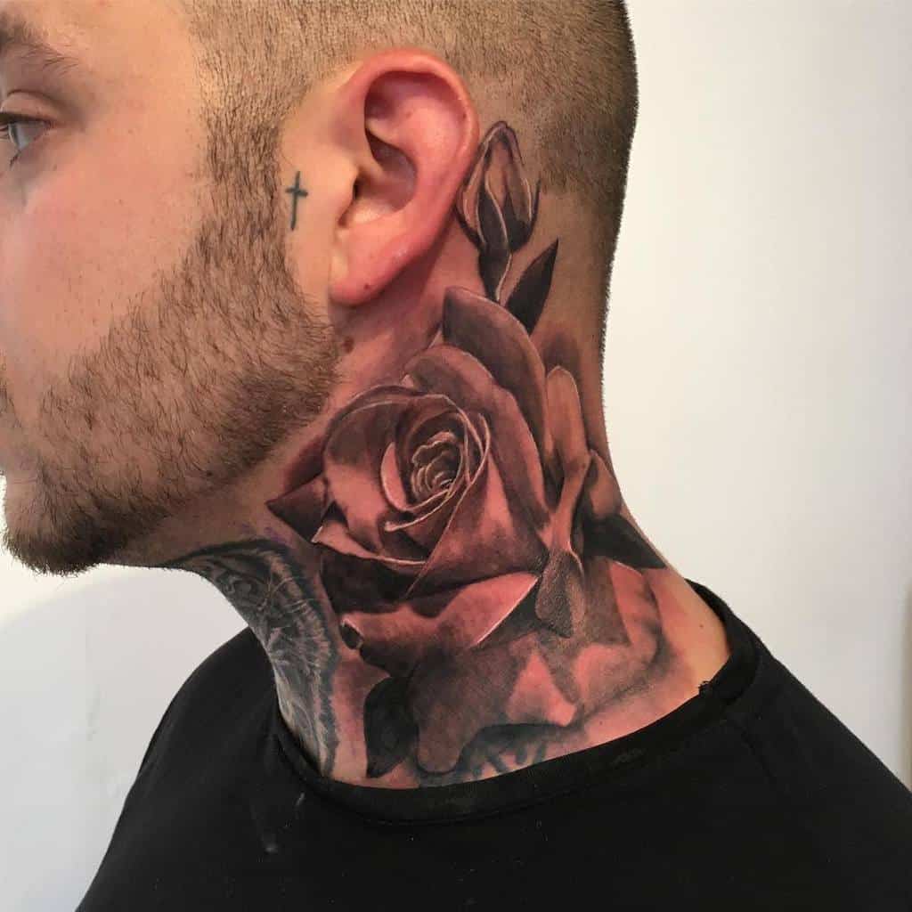 Profile of a man adorned with vibrant body art, featuring a large rose tattoo gracefully blooming across his neck and a discreet cross nestled just behind his ear