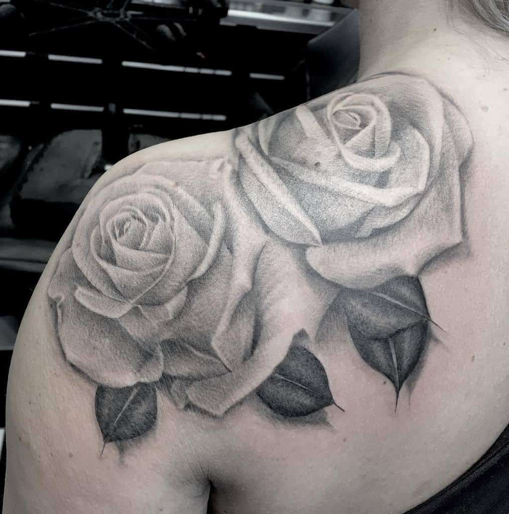 A striking black and gray rose tattoo gracefully adorns the shoulder, adding an elegant touch to the wearer's style