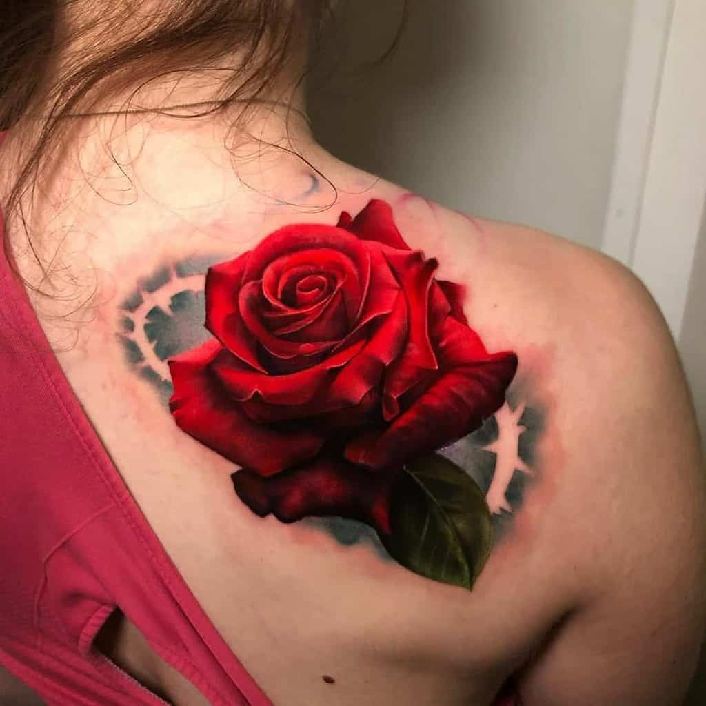 A realistic red rose tattoo adorns the shoulder, elegantly extending across the upper back