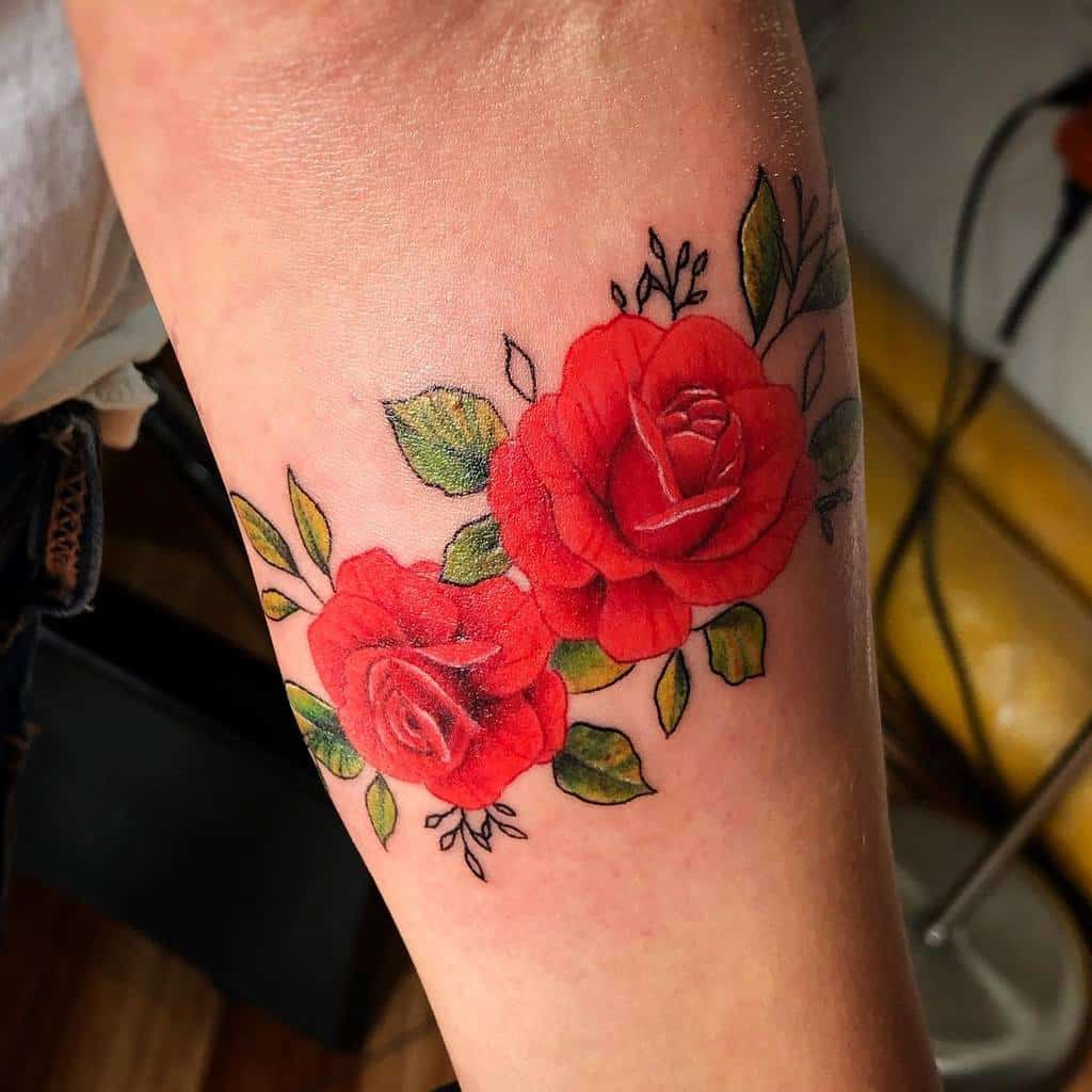Bright and vibrant tattoo featuring two red roses with green leaves and fine details, creating a bold and elegant floral design