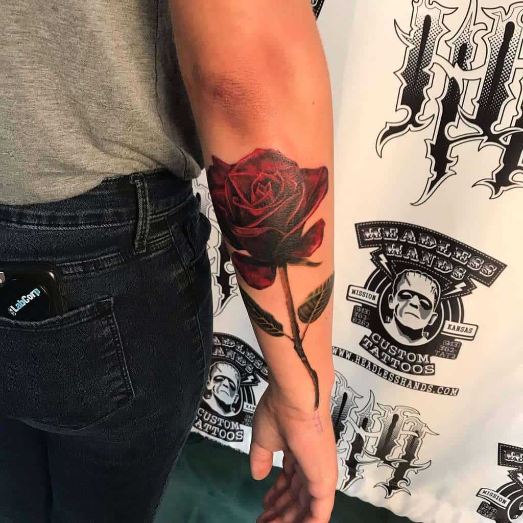 Arm tattoo featuring a large red rose with an elegantly winding stem