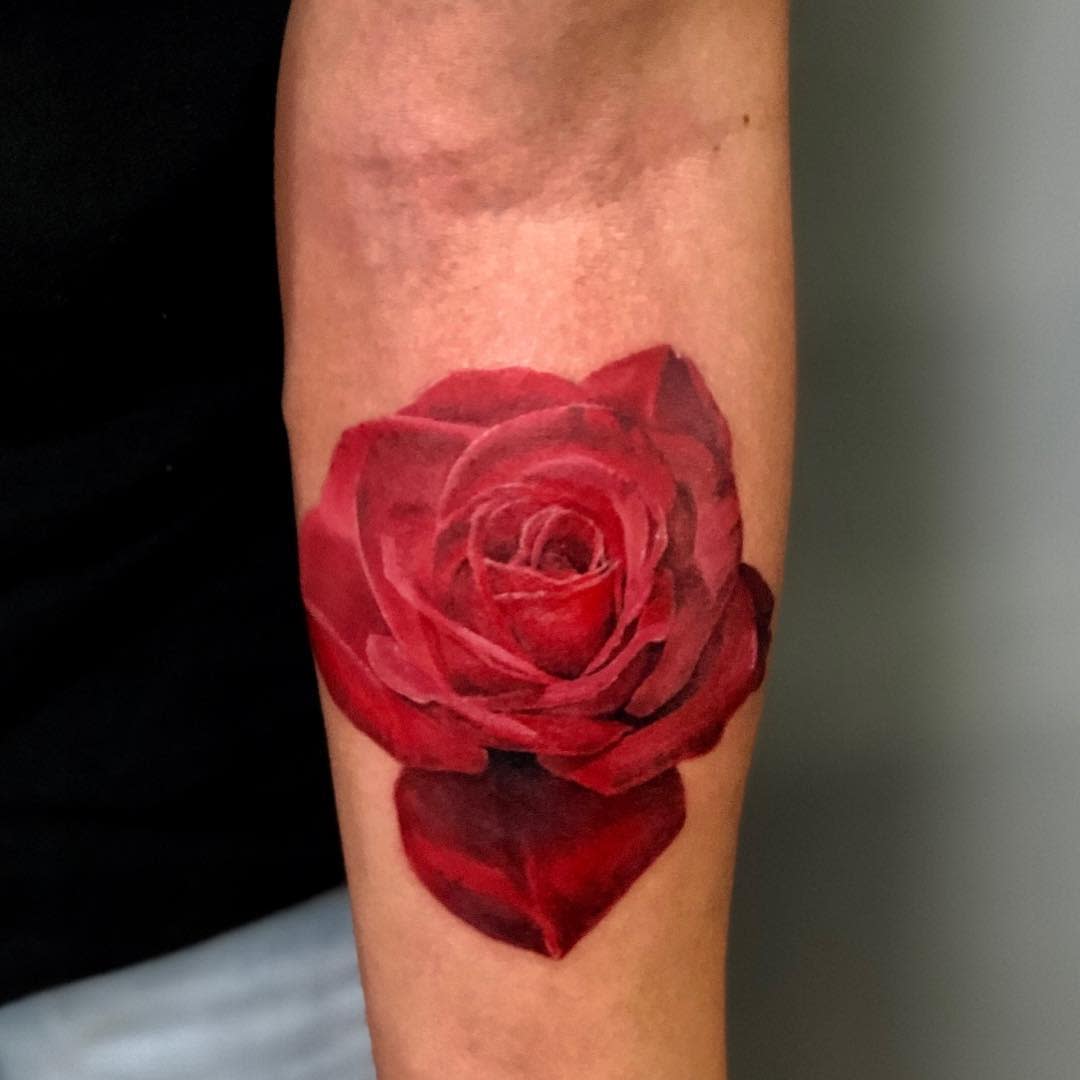 A realistic red rose tattoo on a  forearm
