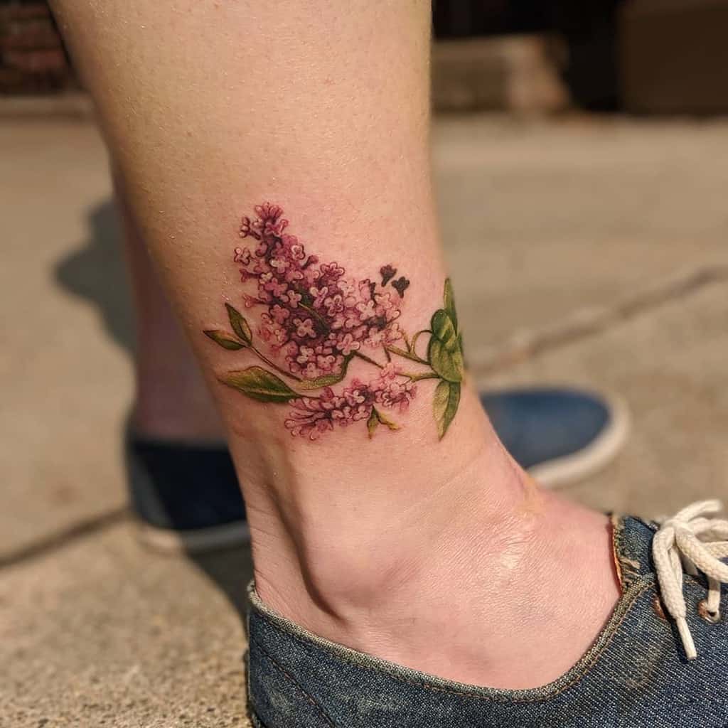 Realistic lilac flower tattoo on the ankle with vibrant purple blooms and green leaves, blending fine details and soft shading.