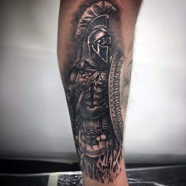 Realistic black and grey tattoo of a Spartan warrior with helmet and shield, symbolizing bravery, discipline, and unwavering strength.