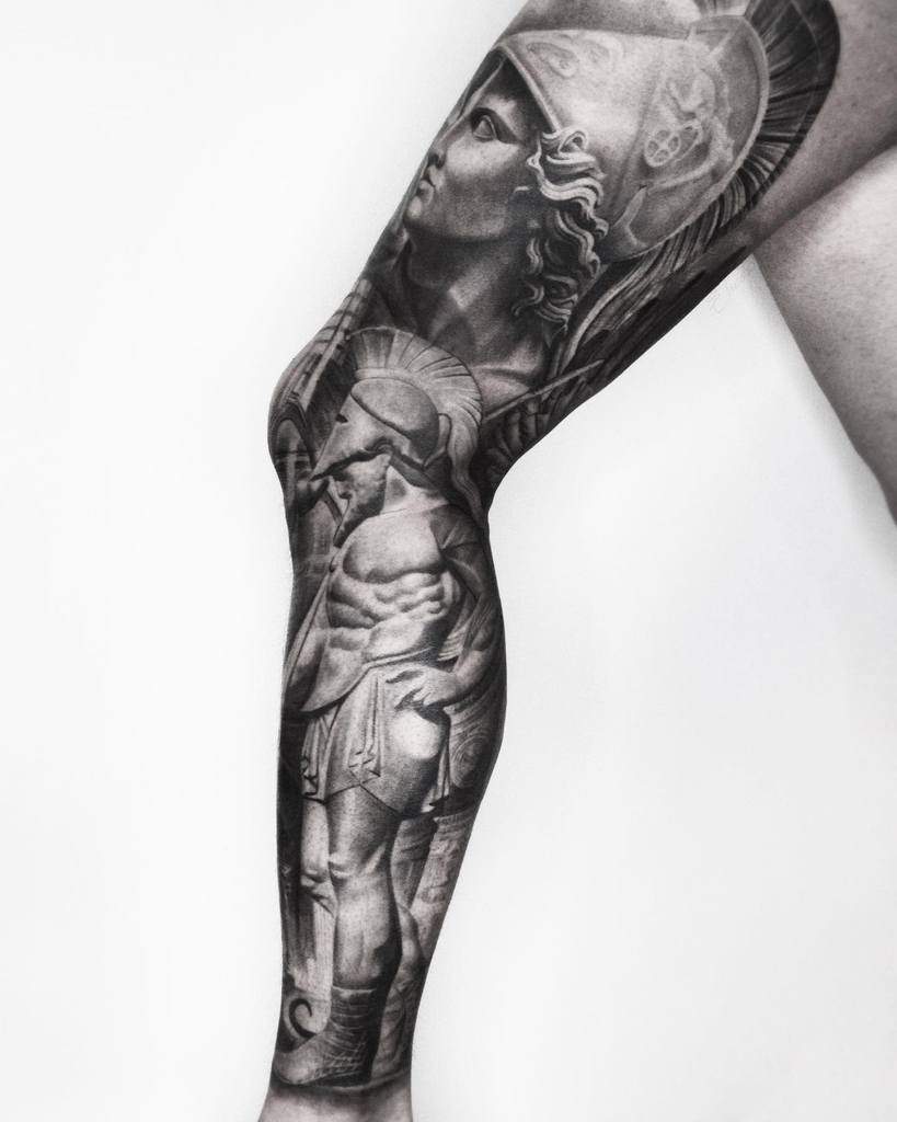 Black and gray tattoo leg sleeve featuring Greek warriors and helmets