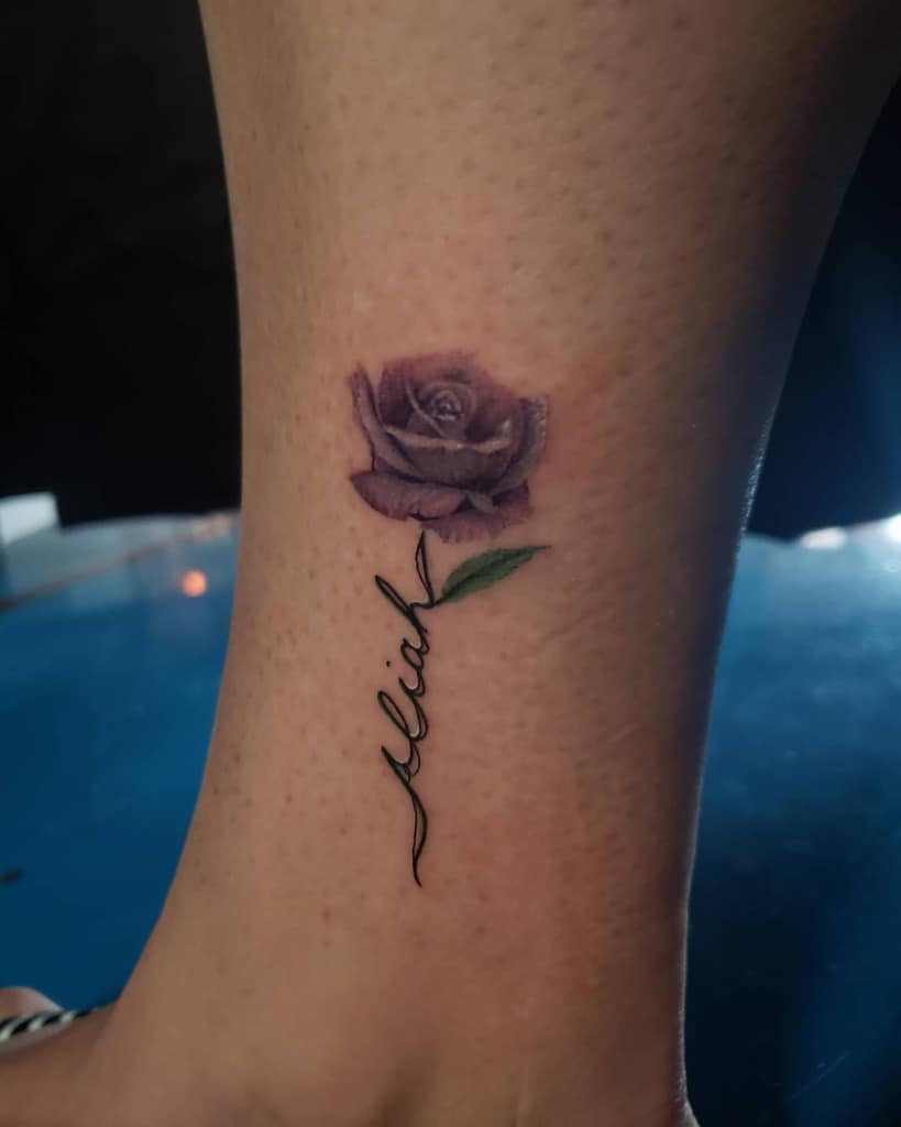 Purple rose tattoo on ankle with the word "aliah" in cursive below it