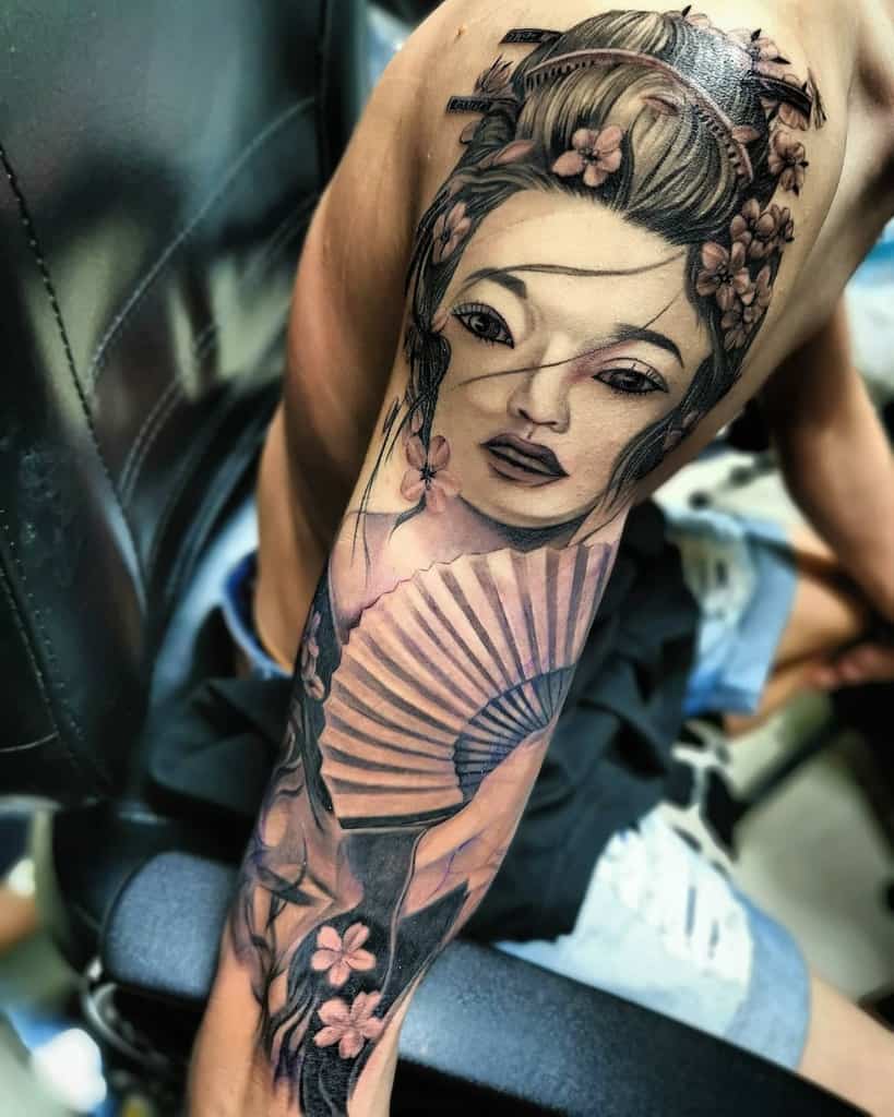 Arm tattoo of a geisha with a fan, featuring delicate flowers and intricate details