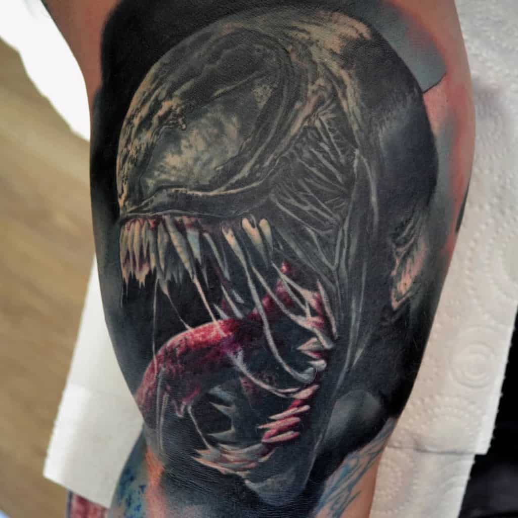 Tattoo of a fierce creature with sharp teeth and a long tongue on an arm