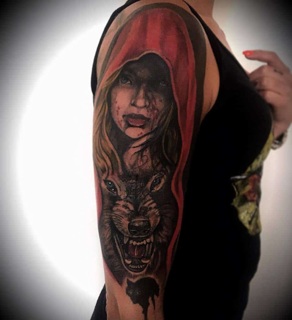 Upper arm tattoo of a woman in a red hood above a snarling wolf, on a woman