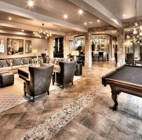 Luxury basement with stone accents, elegant seating, pool table, and crystal chandeliers.