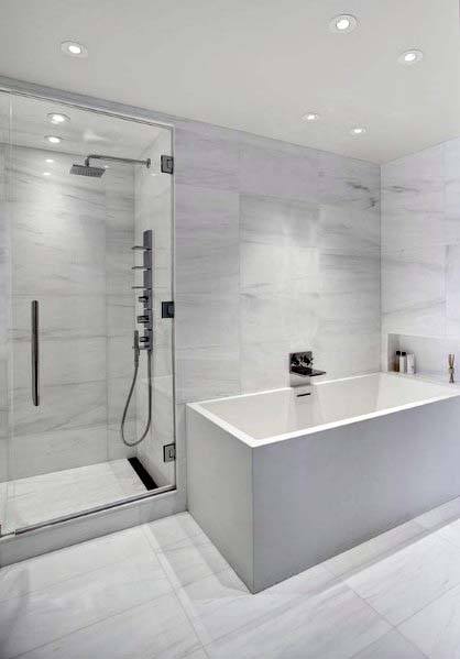Minimalist white bathroom with glass shower, rectangular bathtub, marble surfaces