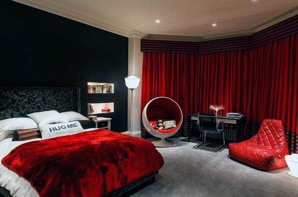 Modern bedroom with a red blanket on the bed, circular chair, and matching red curtains