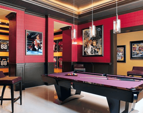Red and black billiards room featuring a pool table, framed sports memorabilia, and pendant lights.