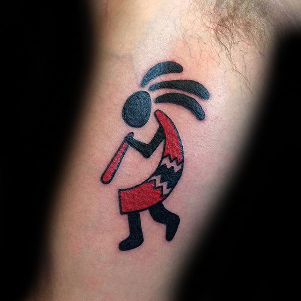 Bold Kokopelli tattoo with black and red colors, featuring tribal patterns on the body and flowing hair, creating a dynamic and stylized appearance.