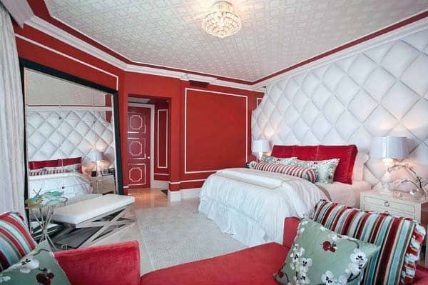 Luxurious red and white bedroom with plush bedding, mirrored closet, and elegant decor