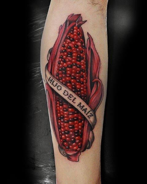 Bold tattoo of a red corn cob with husks, wrapped in a banner reading 'Hijo del Maíz,' featuring rich shading and vibrant details.